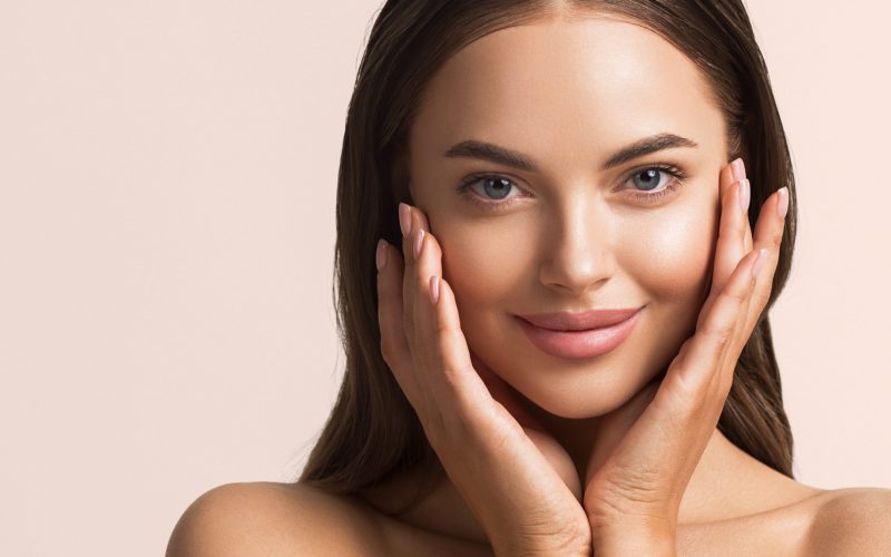 Beautiful woman face close up natural make up hand touching face beauty smile Beautiful woman face close up